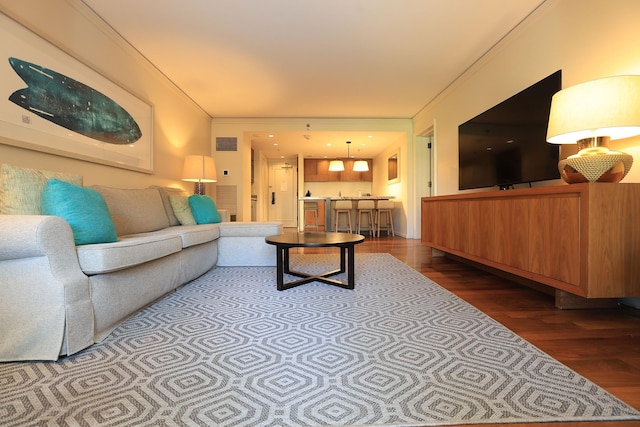 living area with wood finished floors, visible vents, and crown molding