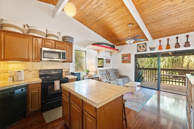 kitchen featuring tile countertops, beamed ceiling, a center island, black appliances, and dark wood-type flooring