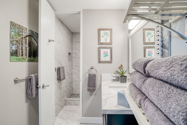 bathroom featuring vanity, a tile shower, and tile patterned flooring