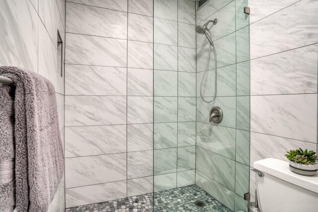 bathroom featuring tiled shower and toilet