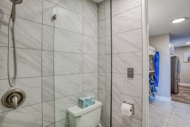 bathroom featuring tiled shower and toilet