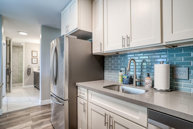 kitchen featuring sink, backsplash, white cabinets, and light wood-type flooring