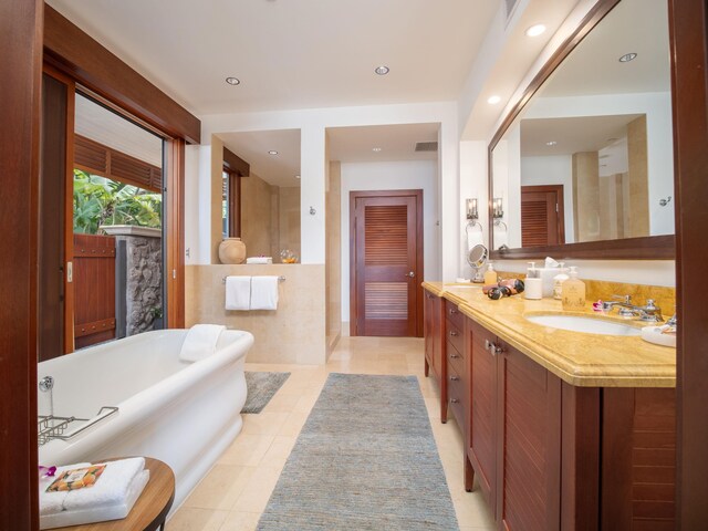 bathroom featuring vanity, a bath, and tile patterned floors