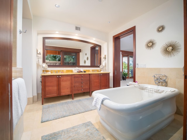 bathroom with a tub, tile patterned floors, and vanity