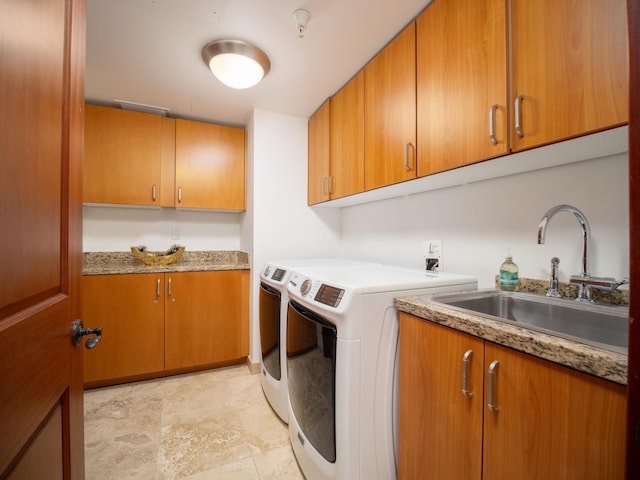 clothes washing area featuring cabinets, sink, and washing machine and dryer