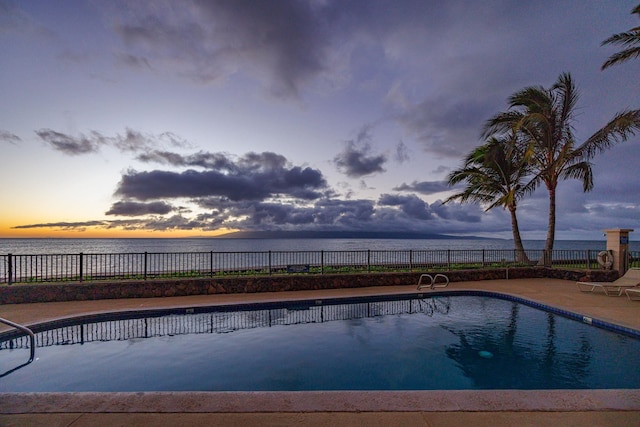 pool at dusk with a fenced in pool, a water view, a patio, and fence