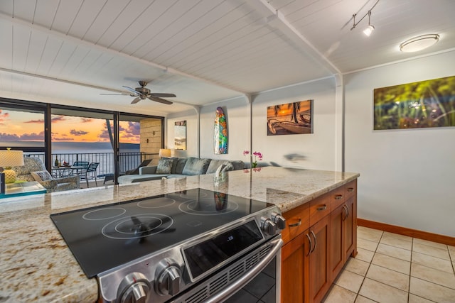 kitchen with light stone counters, stainless steel electric range oven, light tile patterned flooring, ceiling fan, and floor to ceiling windows