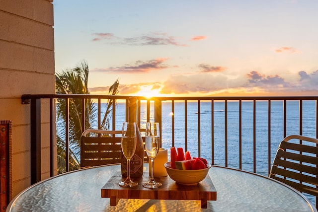 balcony at dusk featuring a water view