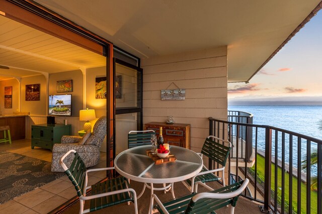 balcony at dusk featuring a water view