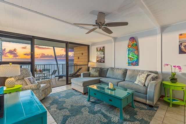 tiled living room with expansive windows, a water view, beam ceiling, and a ceiling fan