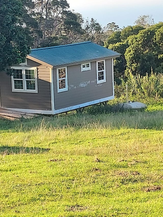 view of home's exterior featuring metal roof, a yard, and an outdoor structure