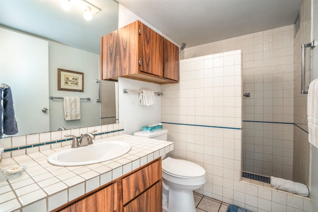 bathroom with vanity, a tile shower, tile walls, toilet, and tile patterned floors