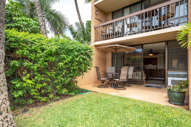 view of yard with a balcony, ceiling fan, and a patio