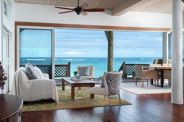 living room with beam ceiling, ceiling fan, dark wood-type flooring, a water view, and wood ceiling