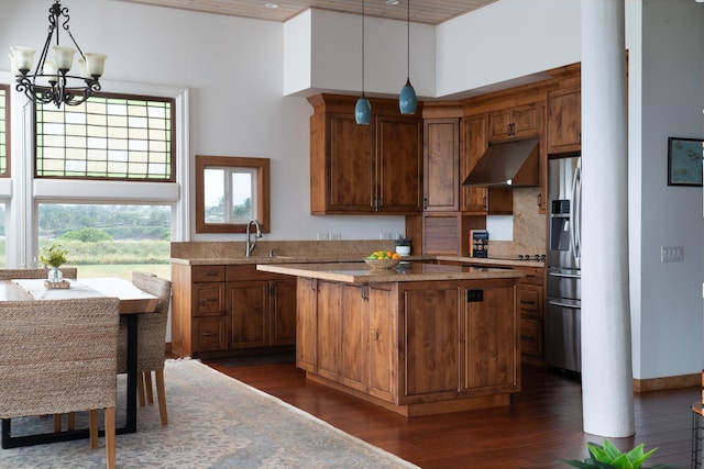 kitchen featuring dark wood-type flooring, stainless steel fridge, a chandelier, pendant lighting, and a kitchen island