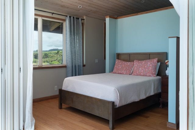 bedroom with light hardwood / wood-style floors, crown molding, and wooden ceiling