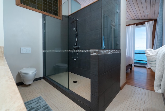 bathroom with a tile shower, toilet, a water view, and hardwood / wood-style flooring