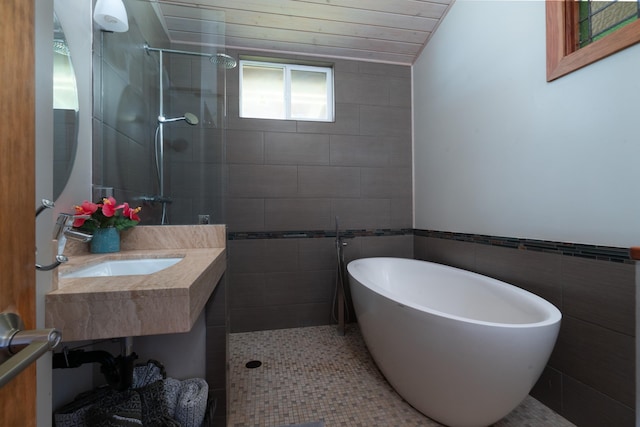 bathroom with tile patterned flooring, tile walls, plus walk in shower, and sink