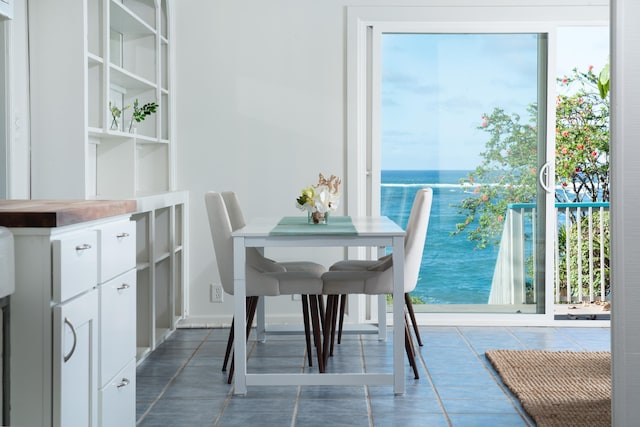 dining room featuring a water view, dark tile patterned floors, and a healthy amount of sunlight