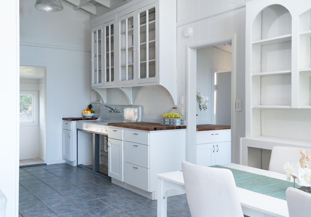 kitchen with wooden counters, white cabinets, dark tile patterned flooring, built in features, and tasteful backsplash