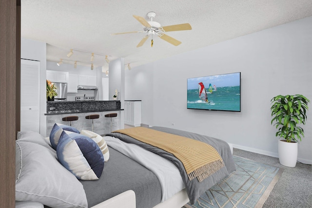 carpeted bedroom featuring rail lighting, ceiling fan, a textured ceiling, and stainless steel refrigerator