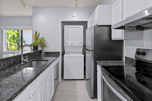 kitchen featuring stacked washing maching and dryer, extractor fan, sink, electric range, and white cabinetry