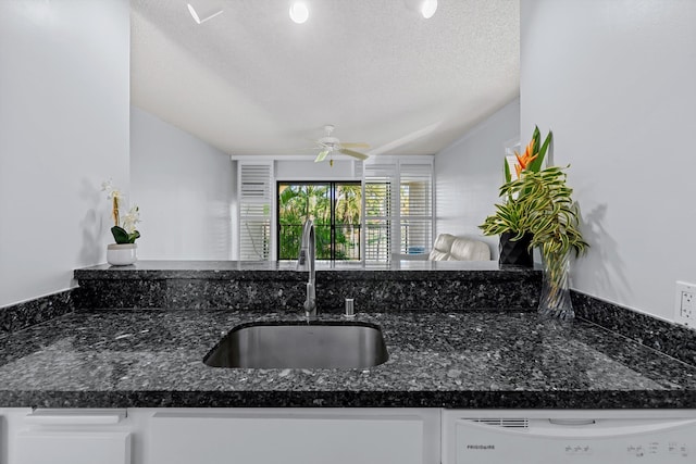 kitchen featuring sink, dark stone countertops, white dishwasher, a textured ceiling, and white cabinets