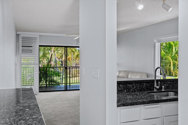 kitchen with carpet, sink, dark stone countertops, a textured ceiling, and white cabinetry