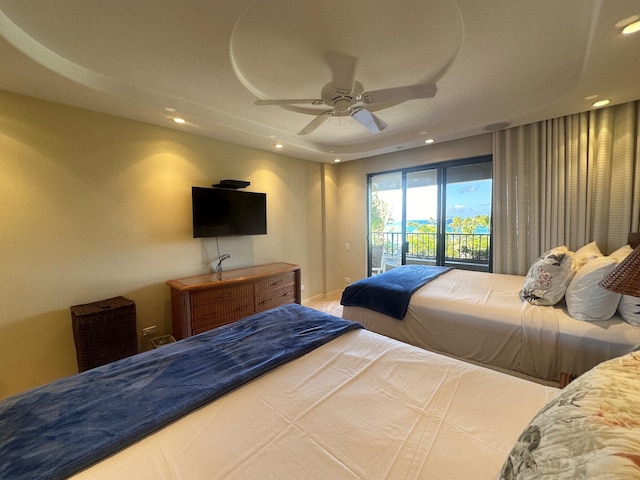 bedroom featuring a tray ceiling, access to exterior, and ceiling fan