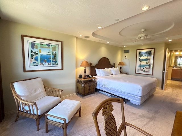 bedroom featuring a textured ceiling, light colored carpet, and ceiling fan