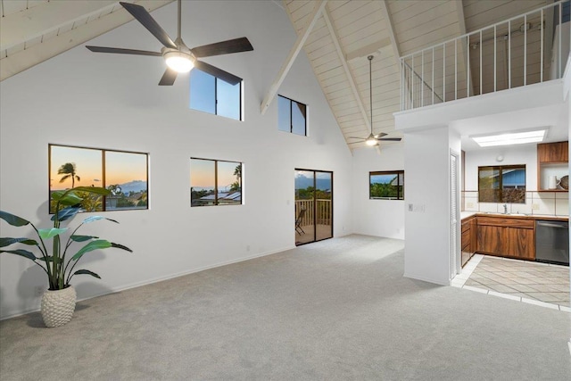 carpeted living room featuring beamed ceiling, high vaulted ceiling, sink, and ceiling fan