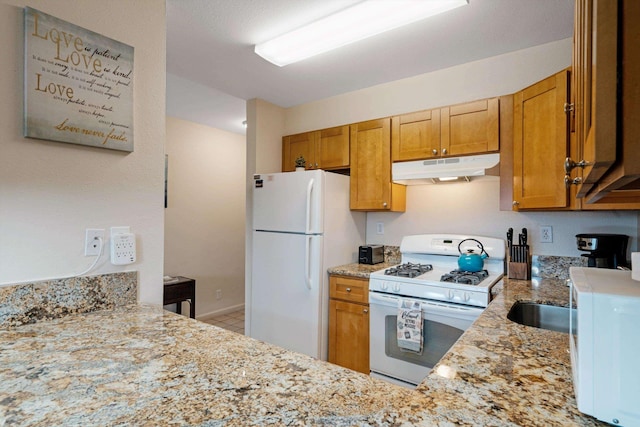 kitchen featuring light stone counters, white appliances, and kitchen peninsula