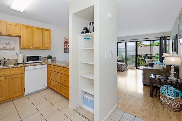 kitchen featuring light stone countertops, sink, light tile patterned floors, and white appliances