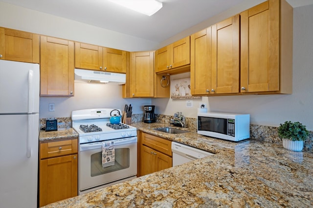 kitchen with white appliances, light stone countertops, and sink