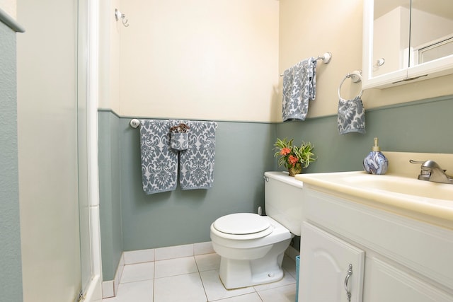 bathroom with tile flooring, vanity, toilet, and a shower with shower door