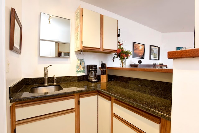 kitchen with dark stone countertops, white cabinets, and sink