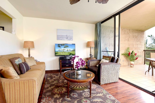 living room with dark hardwood / wood-style floors, ceiling fan, and a wall of windows