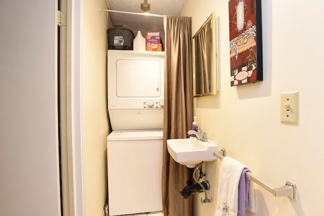 laundry room with sink, stacked washer / dryer, and a textured ceiling