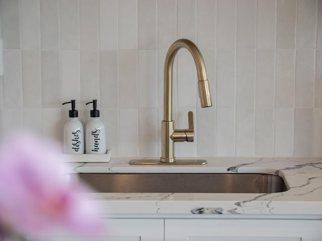 interior details with light stone counters, white cabinets, and a sink