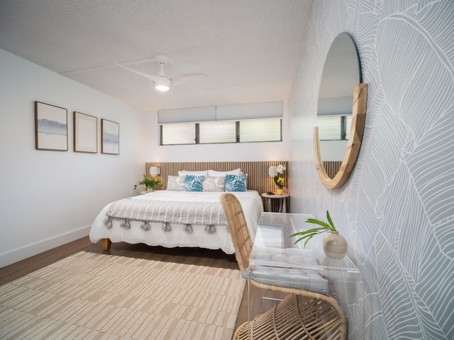 bedroom featuring ceiling fan, a textured ceiling, baseboards, and wood finished floors