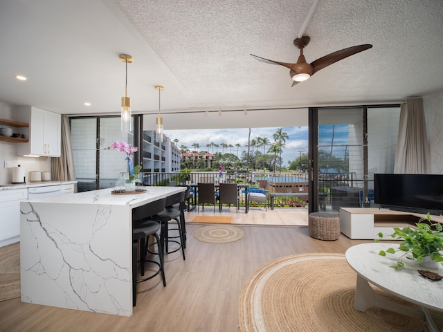 kitchen with a center island, open shelves, white cabinets, light stone countertops, and light wood-type flooring