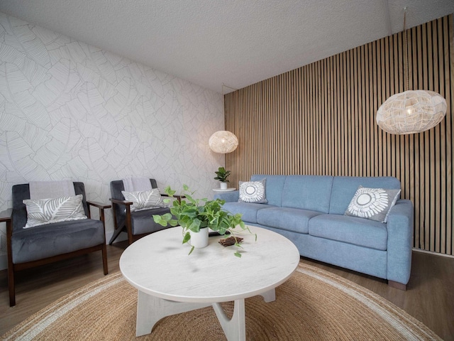 living room with a textured ceiling, wood finished floors, and wallpapered walls