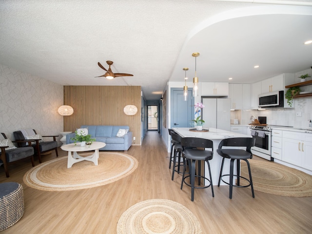 interior space featuring light wood-type flooring, wallpapered walls, a textured ceiling, and recessed lighting