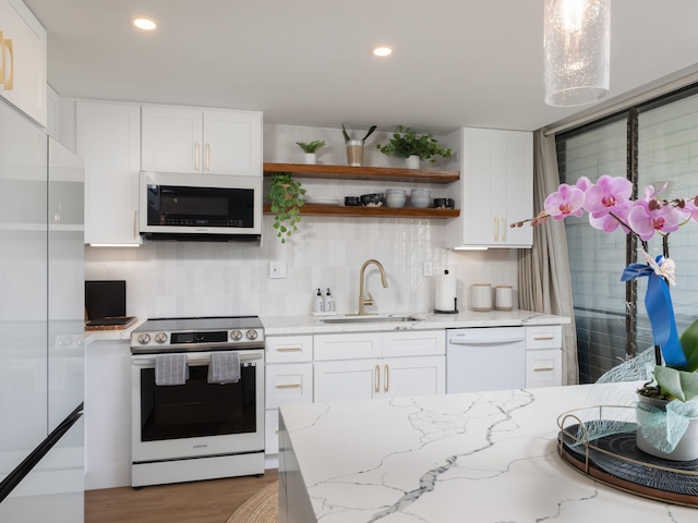 kitchen with white appliances, a sink, white cabinetry, and tasteful backsplash