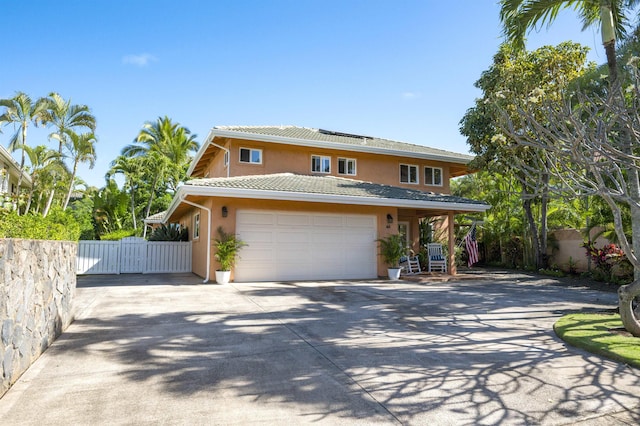 traditional-style home with stucco siding, concrete driveway, fence, a garage, and a tiled roof