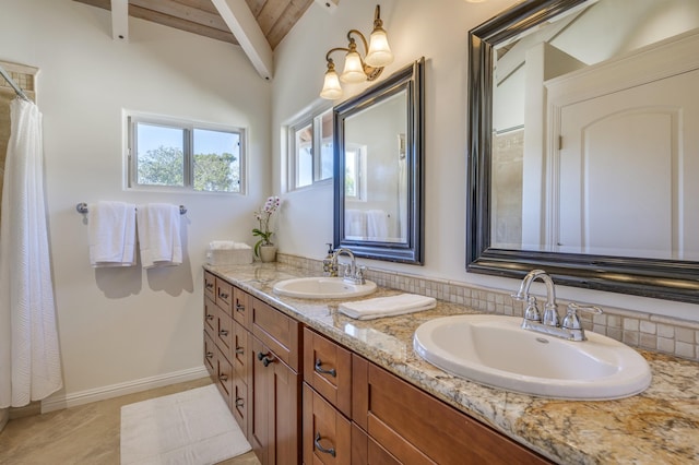 bathroom with double vanity, baseboards, a sink, and beamed ceiling