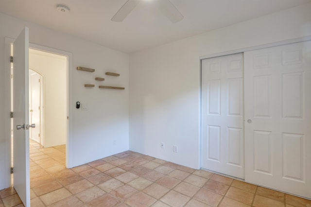 unfurnished bedroom with arched walkways, a closet, and ceiling fan