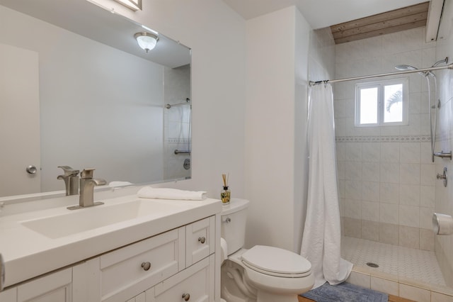 bathroom featuring toilet, tiled shower, and vanity