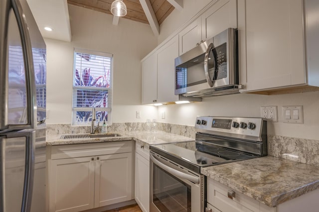 kitchen featuring light stone countertops, white cabinetry, stainless steel appliances, and a sink