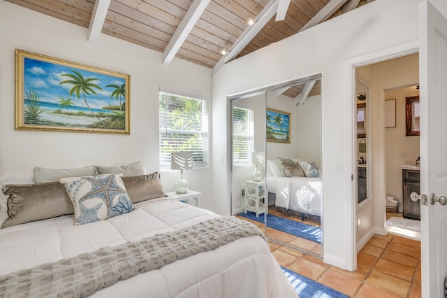 bedroom with light tile patterned floors, a closet, lofted ceiling with beams, wooden ceiling, and baseboards